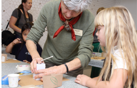 Volunteer helping young girl with art project.