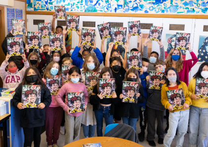 Classroom holding up free "We Can" books through Arts Access program.