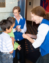 Two volunteer ushers greeting Arts Access children for a matinee performance.