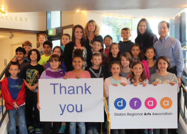 Students standing, holding thank you signs alongside adult sponsors